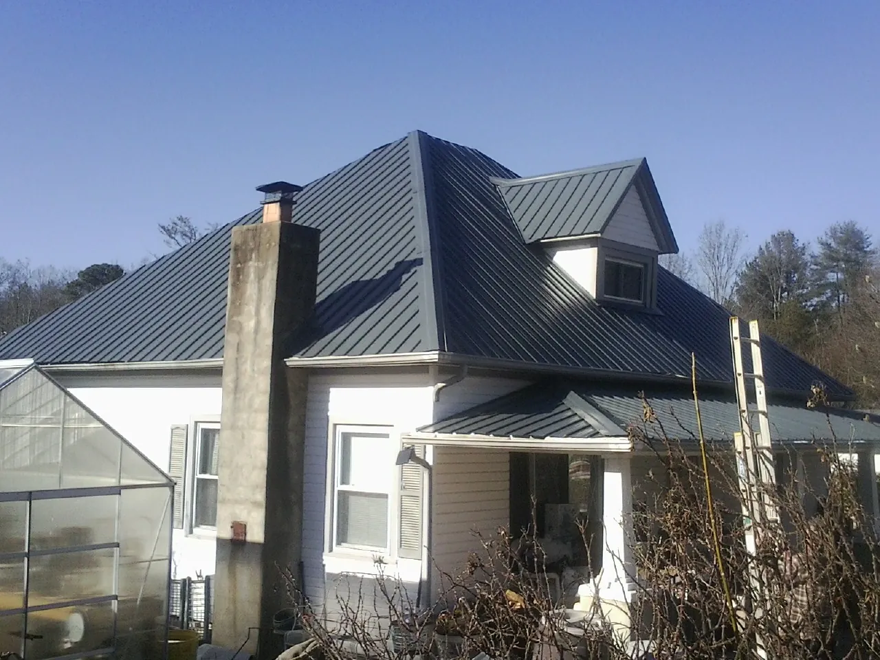 Dark blue standing seam metal roof on a white farmhouse with dormer — Slate & Tile Roof Repair by Roofing Brothers in Mount Aetna