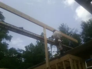 Carpenter setting a ridge beam over a new addition frame — Ice Dam Removal by Roofing Brothers in Mount Aetna