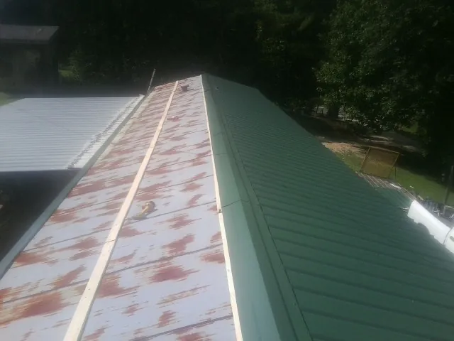 Old rusted panels beside newly installed green metal roofing — Wind Damage Roof Repair by Roofing Brothers in Mount Aetna