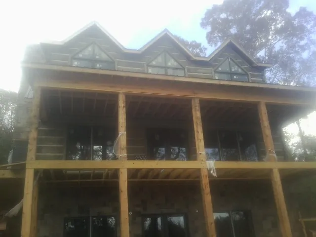 Dormers and porch framing on a large log home under construction — Roof Coating work by our crew in Mount Aetna