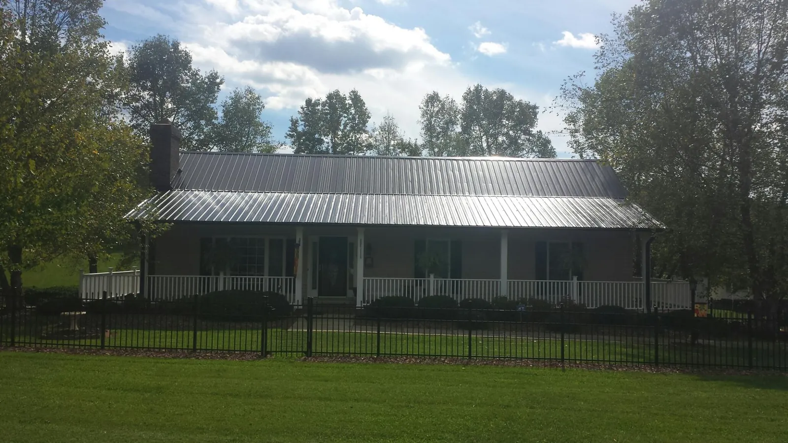 Gray metal roof on a brick ranch with a full width front porch — Gutter Guard Installation work by our crew in Mount Aetna