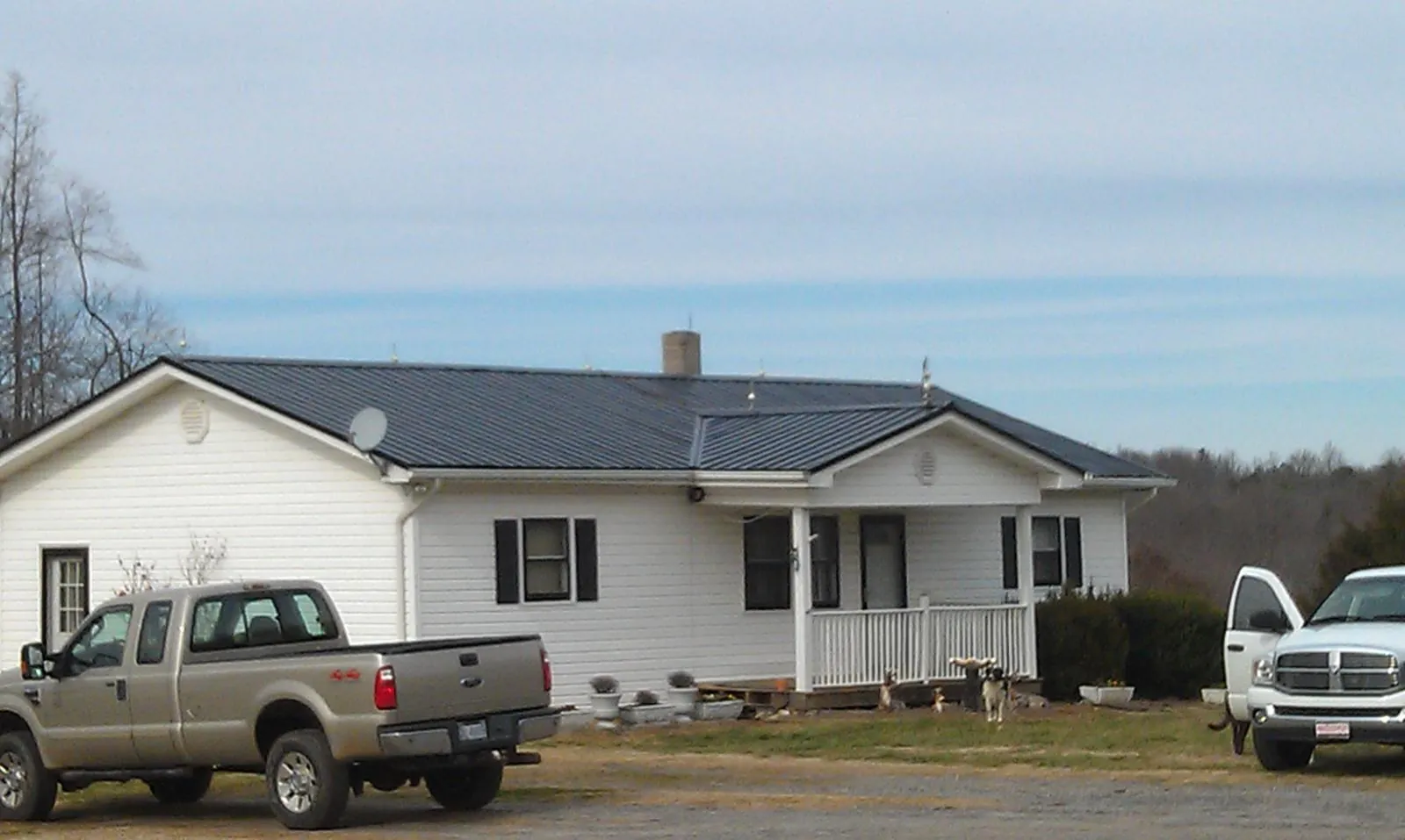 Finished dark metal roof on a white ranch home with work trucks parked in Mount Aetna