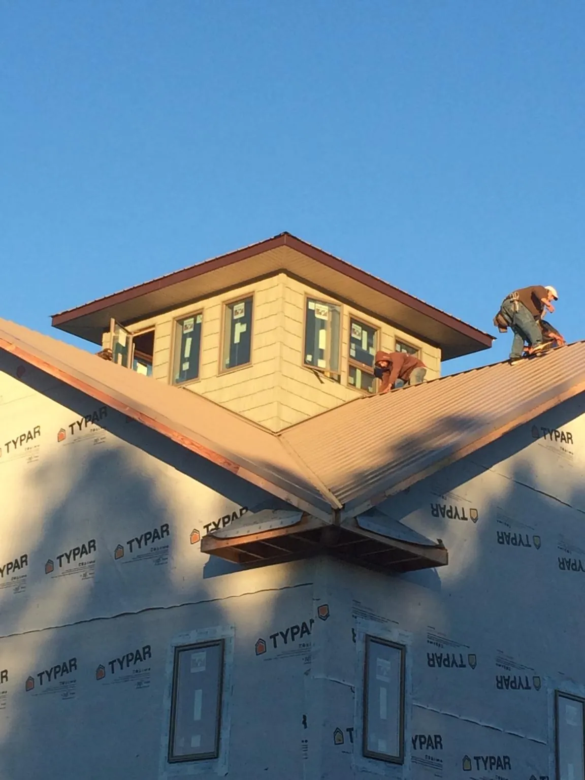 Roofers working around a rooftop cupola on a new metal roof at sunset — Roof Waterproofing in Mount Aetna by Roofing Brothers